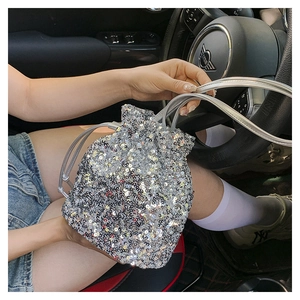 Détail d'un sac seau à paillettes argentées avec cordon de serrage dans un habitacle de voiture