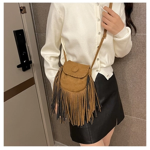 Detailed view of a brown suede saddle bag with fringe details on a fashion model