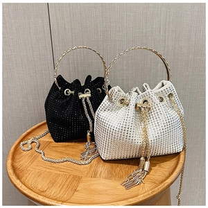 Détail de sacs seaux en strass avec poignées dorées et cordons à glands pour soirée