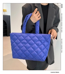 Detailed close-up of quilted blue puffer tote bag with diamond stitching and soft texture