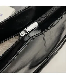 Macro shot of silver metal zipper puller and textured black leather surface on bag