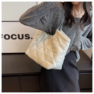 Close-up of white quilted leather tote with silver chain strap shown on a model