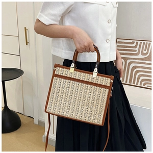 Detailed texture of handwoven straw tote bag with brown leather trim and amber handle