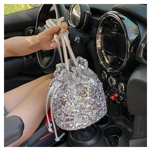 Détail du sac seau à paillettes argentées avec cordon de serrage tenu dans une voiture