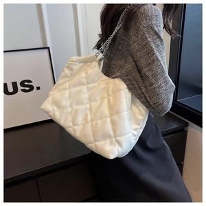 Detailed view of white quilted faux leather tote bag with silver chain straps and large capacity