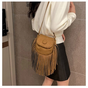 Close-up of brown suede crossbody bag featuring long bohemian tassels and woven stitching