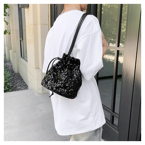 Vue détaillée d'un sac seau noir à paillettes avec cordon et fine bandoulière en cuir