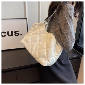 Detailed close-up of white quilted chain shoulder bag with elegant silver strap detail