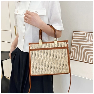 Detail of straw tote bag with amber handles and leather trim on a model