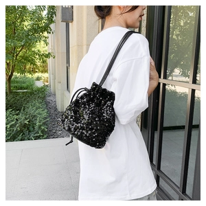 Détail d'un sac seau chic à paillettes noires avec fermeture à cordon sur modèle