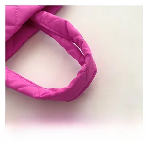 Close-up of comfortable padded handle on fuchsia quilted tote bag with diamond stitching