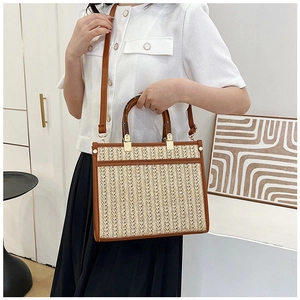 Detailed view of the woven tote bag featuring tortoiseshell handles and a brown leather pocket