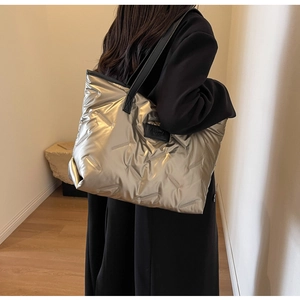 Détail du grand sac cabas argenté matelassé avec poignées en cuir et badge de mode