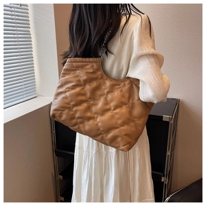 Quilted tote bag with chain strap shown on model for capacity and style reference