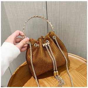 Détail du sac seau marron de luxe avec strass dorés, poignée en métal et glands élégants