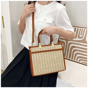 Detail view of woven straw tote bag with brown leather trim and tortoiseshell handles