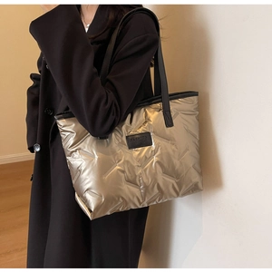 Détail du sac cabas matelassé doré métallisé avec étiquette en cuir noir et bandoulière