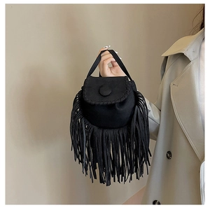 Detailed view of bohemian black faux suede handbag with long tassels and button closure