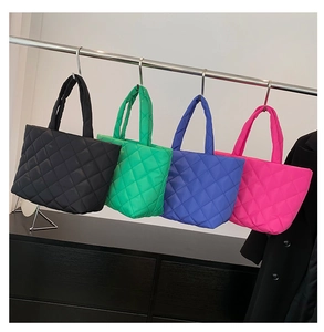 Detail of four vibrant quilted puffer tote bags in black, green, blue and rose pink