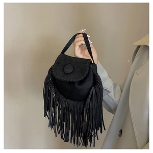 Close-up of black suede saddle bag featuring dense fringe tassels and round button closure