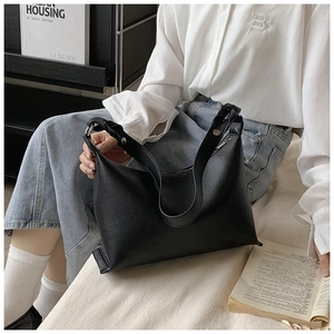 Dettaglio di grande borsa tote in pelle nera a grana litchi con tracolla larga