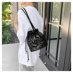 Détail du sac seau à paillettes noires avec cordon de serrage et fines bretelles en cuir
