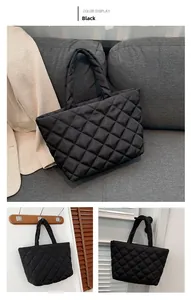 Detail of black quilted puffer tote bag on a gray sofa for a casual daily commute