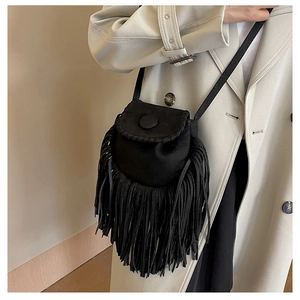 Close-up of bohemian black suede saddle bag featuring woven edges and long fringes