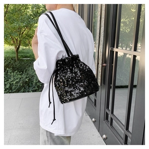 Sac seau à paillettes noires avec cordon de serrage porté sur un T-shirt blanc ample