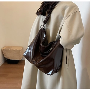 Detail of dark brown glossy leather Hobo bag with wide shoulder strap and spiral wrap