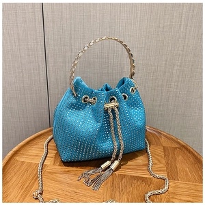 Gros plan du sac seau en velours sarcelle avec strass brillants et glands dorés