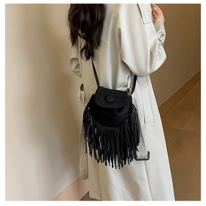 Detailed view of black suede crossbody bag featuring long fringe and stitching details