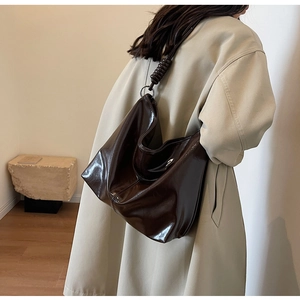 Detail of a large chocolate brown leather hobo bag with thick spiral shoulder strap detail