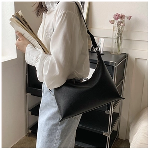 Vista laterale dettagliata di una grande borsa hobo in pelle nera martellata indossata da modella