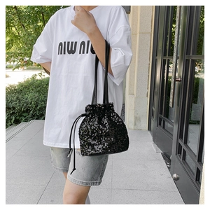Détail d'un sac seau chic à paillettes noires avec cordon de serrage et bandoulière