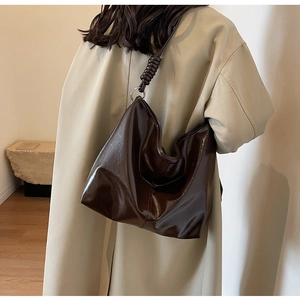 Close-up of dark brown glossy tote bag showing textured soft leather and spiral strap detail