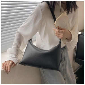 Dettaglio della borsa hobo in pelle nera minimalista indossata da modella in stile casual