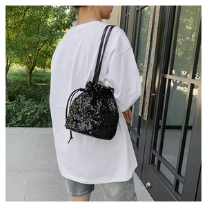 Détail d'un sac seau noir à paillettes avec fermeture à cordon sur un mannequin