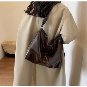 Detail of dark brown leather tote with large silver metal rings and woven strap detail