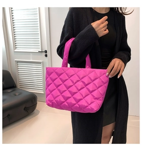 Detail of hot pink quilted puffer tote bag with diamond pattern shown on model