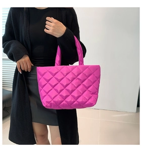 Detail of hot pink quilted tote bag with padded handles and glossy textured fabric finish