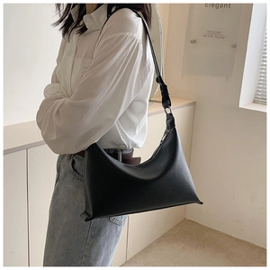 Primo piano di una borsa hobo in pelle nera martellata portata a spalla da una modella