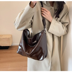 Detailed view of dark brown oversized hobo bag with unique knotted strap and shiny leather finish