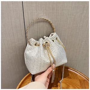 Détail d'un sac seau en strass étincelants avec pompons dorés et poignée métallique