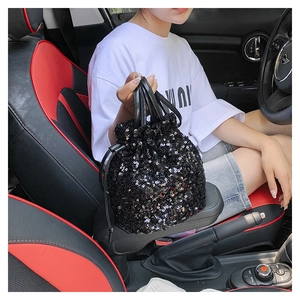 Détail du sac seau à paillettes noires avec cordon et poignées en cuir dans l'auto