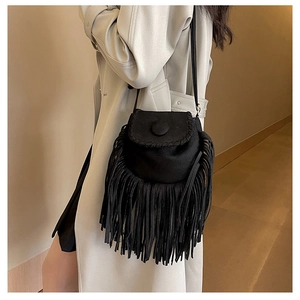 Detail of black suede saddle bag with fringe tassels and magnetic snap closure on model