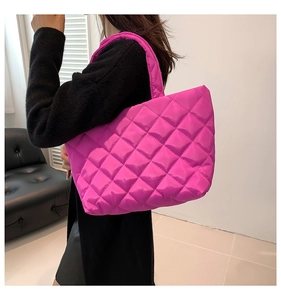 Detail of hot pink quilted tote bag with diamond pattern and glossy finish on model