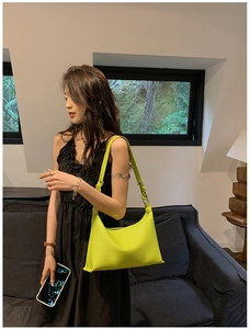 Dettaglio di una borsa hobo a mezzaluna verde lime abbinata a un abito nero elegante