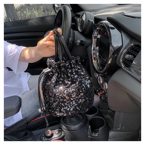 Détail d'un sac seau noir à paillettes avec fermeture à cordon et texture scintillante