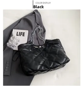 Detail shot of a black quilted tote bag with silver chain straps on a grey blazer